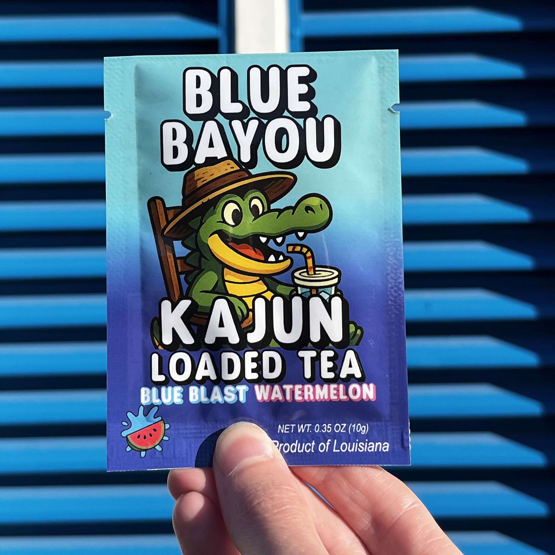 Blue Bayou Kajun Loaded Tea packet held in front of blue slatted background