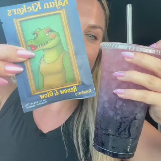 Woman sitting in a car holding a purple iced drink and a packet that reads Kajun Kickers.